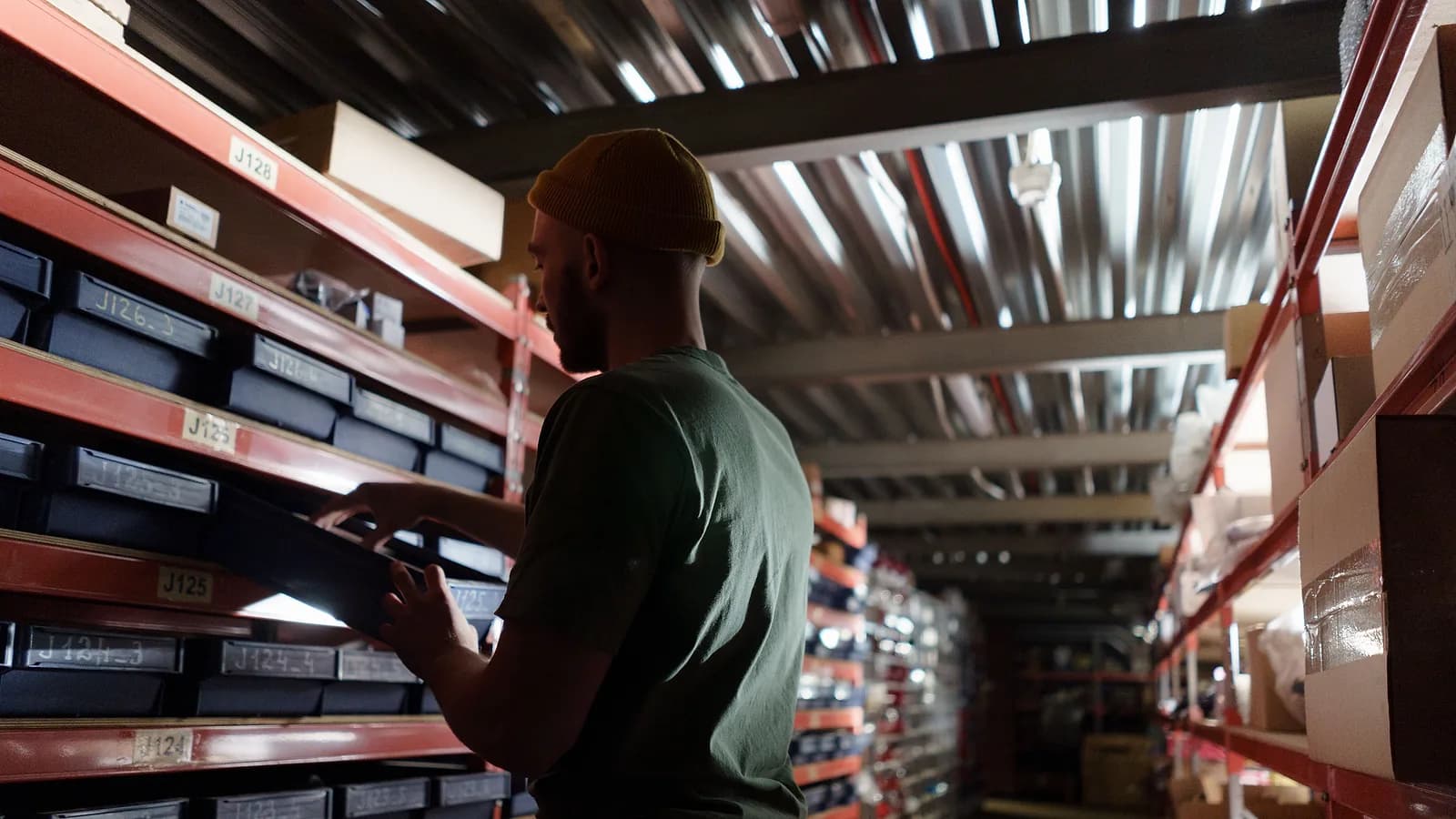 Magazziniere che preleva una cassetta dagli scaffali di un magazzino di distribuzione